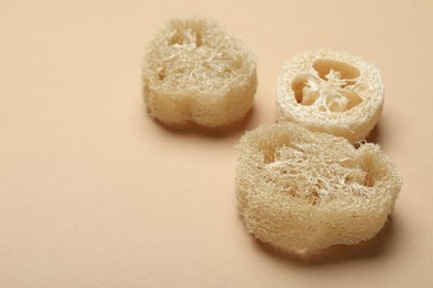 Photo of Natural loofah sponges on beige background, closeup. Space for text