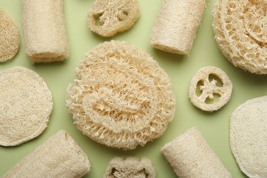 Photo of Natural loofah sponges on green background, flat lay