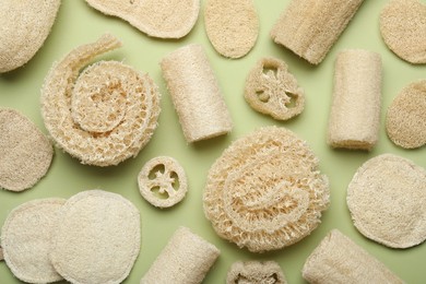 Photo of Natural loofah sponges on green background, flat lay