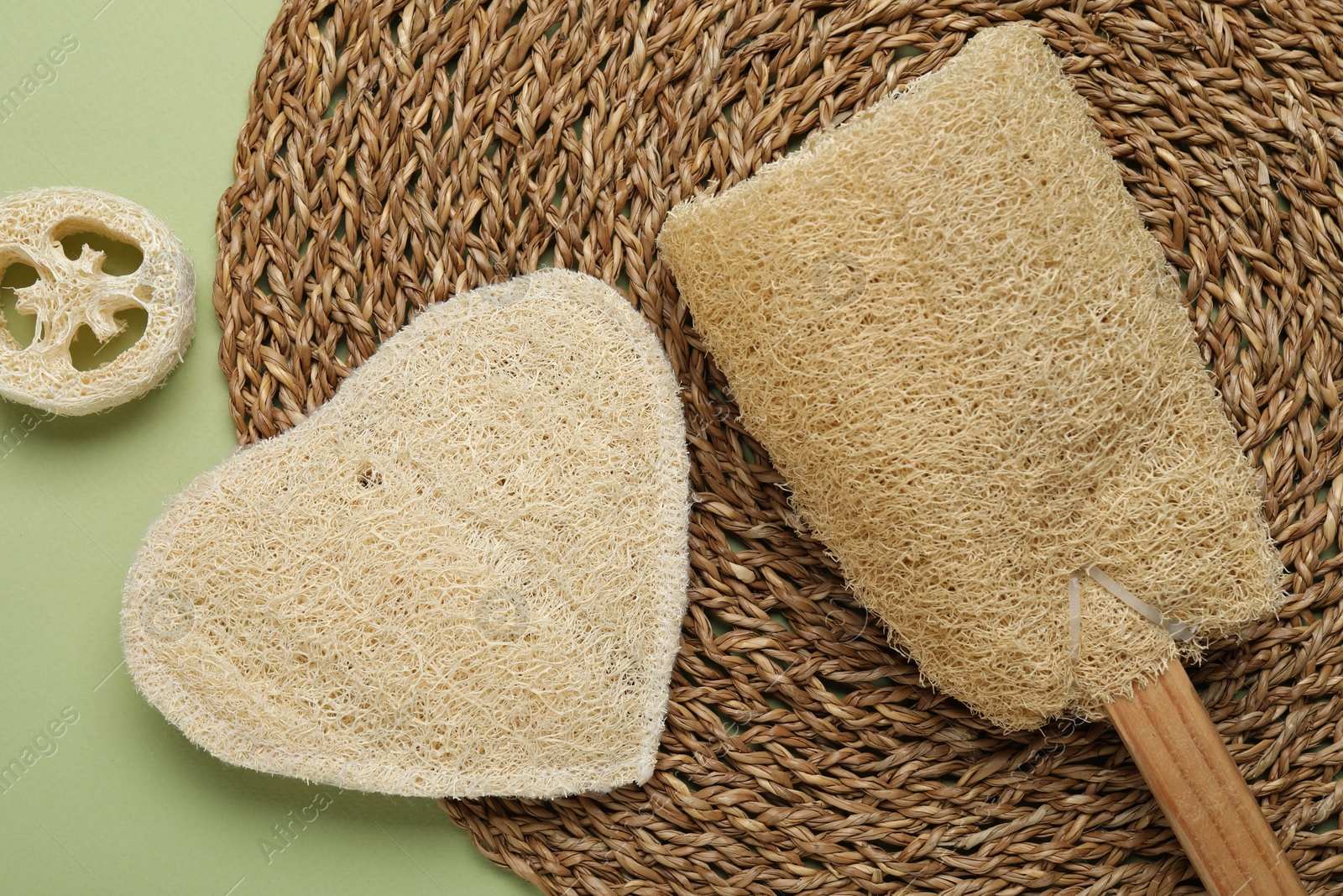 Natural loofah sponges on green background, flat lay Photo of Natural loofah sponges on green background, flat lay