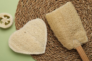 Photo of Natural loofah sponges on green background, flat lay