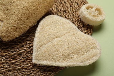 Photo of Natural loofah sponges on green background, closeup