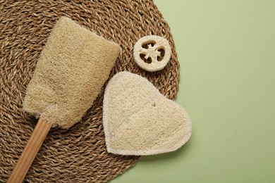 Photo of Natural loofah sponges on green background, flat lay. Space for text