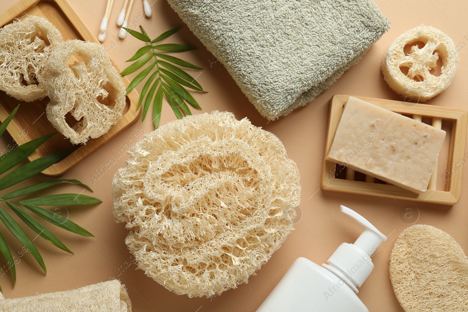Natural loofah sponges, towel, soap, cosmetic product, swabs and twigs on beige background, flat lay Photo of Natural loofah sponges, towel, soap, cosmetic product, swabs and twigs on beige background, flat lay