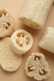 Photo of Natural loofah sponges on beige background, flat lay