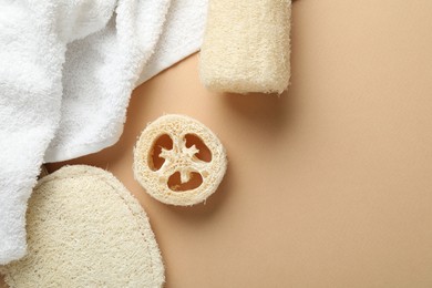 Photo of Natural loofah sponges and towel on beige background, flat lay. Space for text
