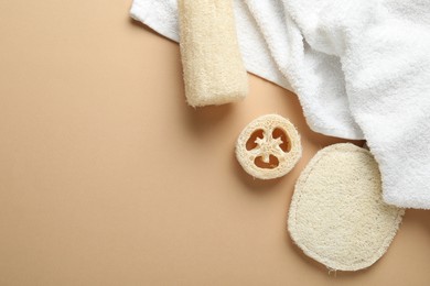 Photo of Natural loofah sponges and towel on beige background, flat lay. Space for text