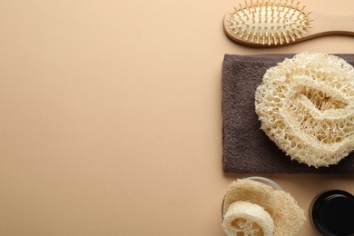 Photo of Natural loofah sponges, cosmetic product, towel and brush on beige background, flat lay. Space for text