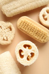 Photo of Natural loofah sponges and brush on beige background, flat lay