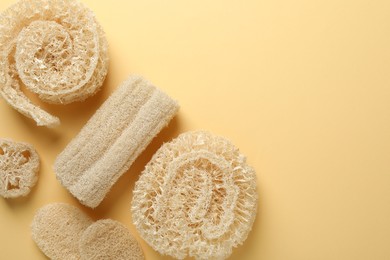 Photo of Natural loofah sponges on beige background, flat lay. Space for text