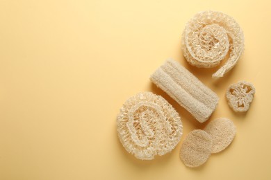 Photo of Natural loofah sponges on beige background, flat lay. Space for text
