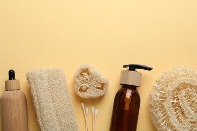 Photo of Natural loofah sponges, cosmetic products and swabs on beige background, flat lay. Space for text