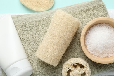 Photo of Natural loofah sponges, cosmetic products and towels on light blue background, top view