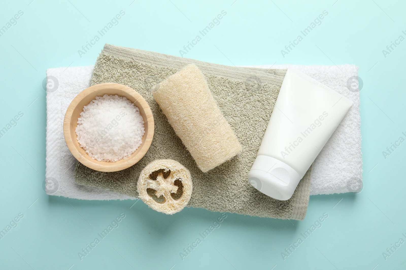 Natural loofah sponges, cosmetic products and towels on light blue background, top view Photo of Natural loofah sponges, cosmetic products and towels on light blue background, top view