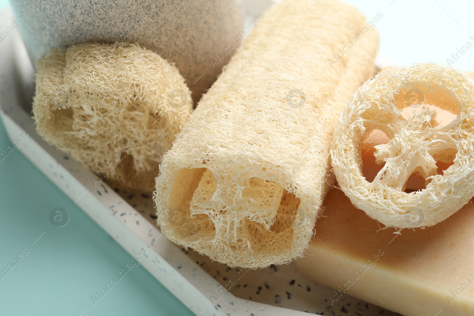 Natural loofah sponges and soap on light blue background, closeup Photo of Natural loofah sponges and soap on light blue background, closeup