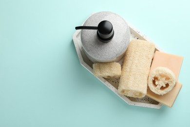 Photo of Natural loofah sponges, cosmetic product and soap on light blue background, top view. Space for text
