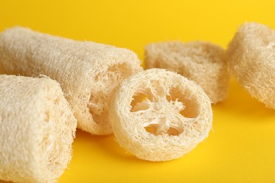 Photo of Natural loofah sponges on yellow background, closeup