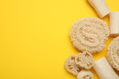 Photo of Natural loofah sponges on yellow background, flat lay. Space for text