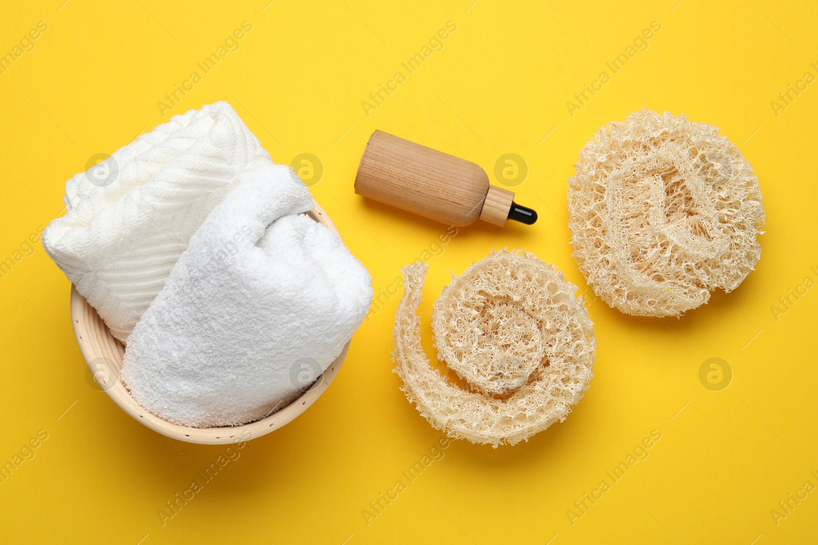Natural loofah sponges, cosmetic product and towels on yellow background, flat lay Photo of Natural loofah sponges, cosmetic product and towels on yellow background, flat lay