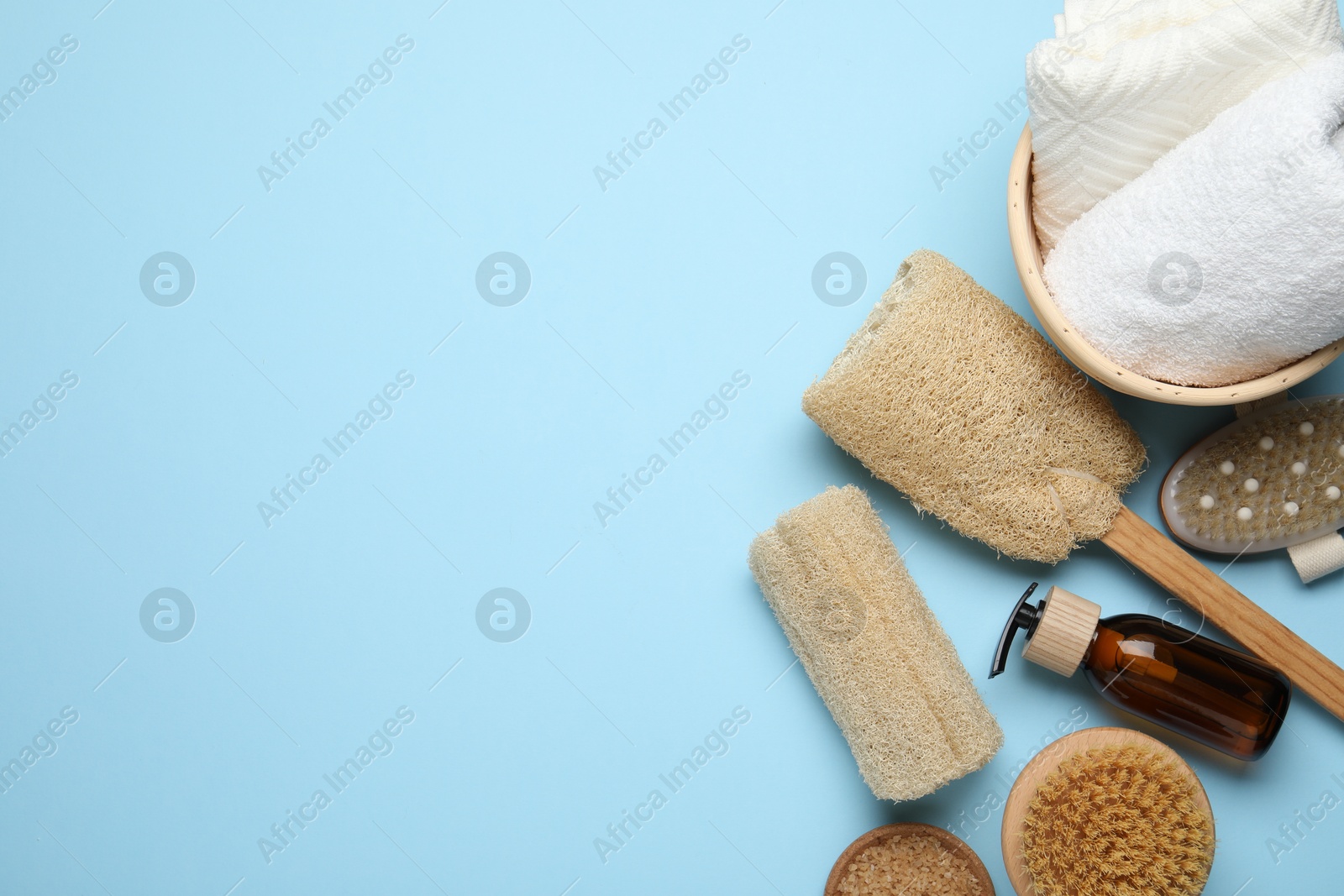 Natural loofah sponges, cosmetic product, brushes and towels on light blue background, flat lay. Space for text Photo of Natural loofah sponges, cosmetic product, brushes and towels on light blue background, flat lay. Space for text