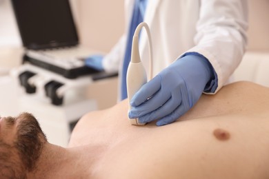 Photo of Sonographer conducting ultrasound examination of man's heart in clinic, closeup