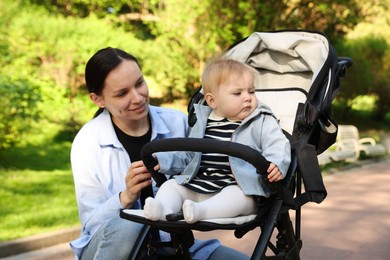 Photo of Mother with her cute baby in stroller at park