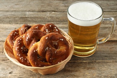 Photo of Tasty pretzels and glass of beer on wooden table, closeup