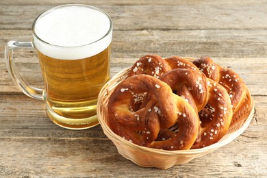 Photo of Tasty pretzels and glass of beer on wooden table, closeup