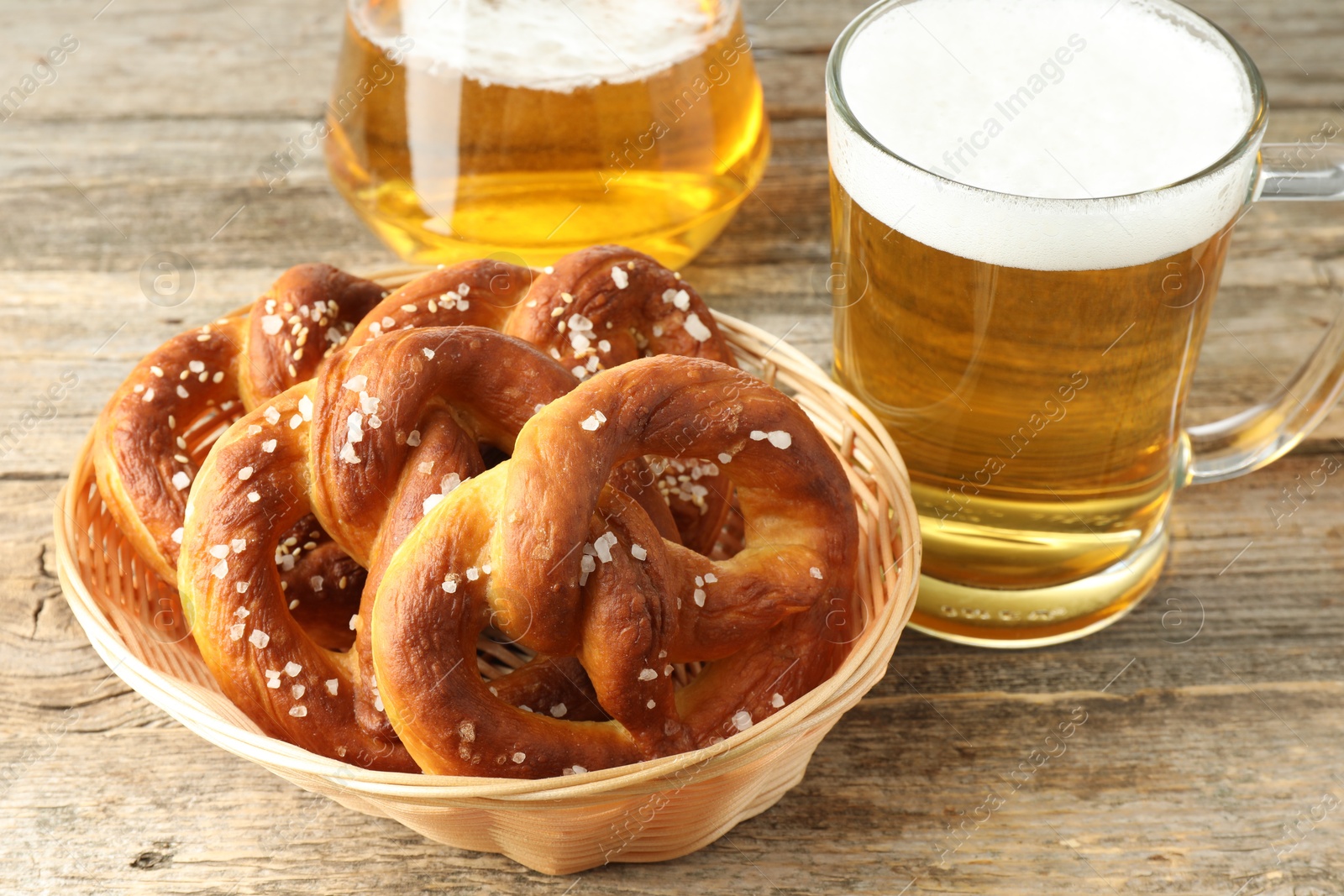 Tasty pretzels in basket and glasses of beer on wooden table, closeup Photo of Tasty pretzels in basket and glasses of beer on wooden table, closeup