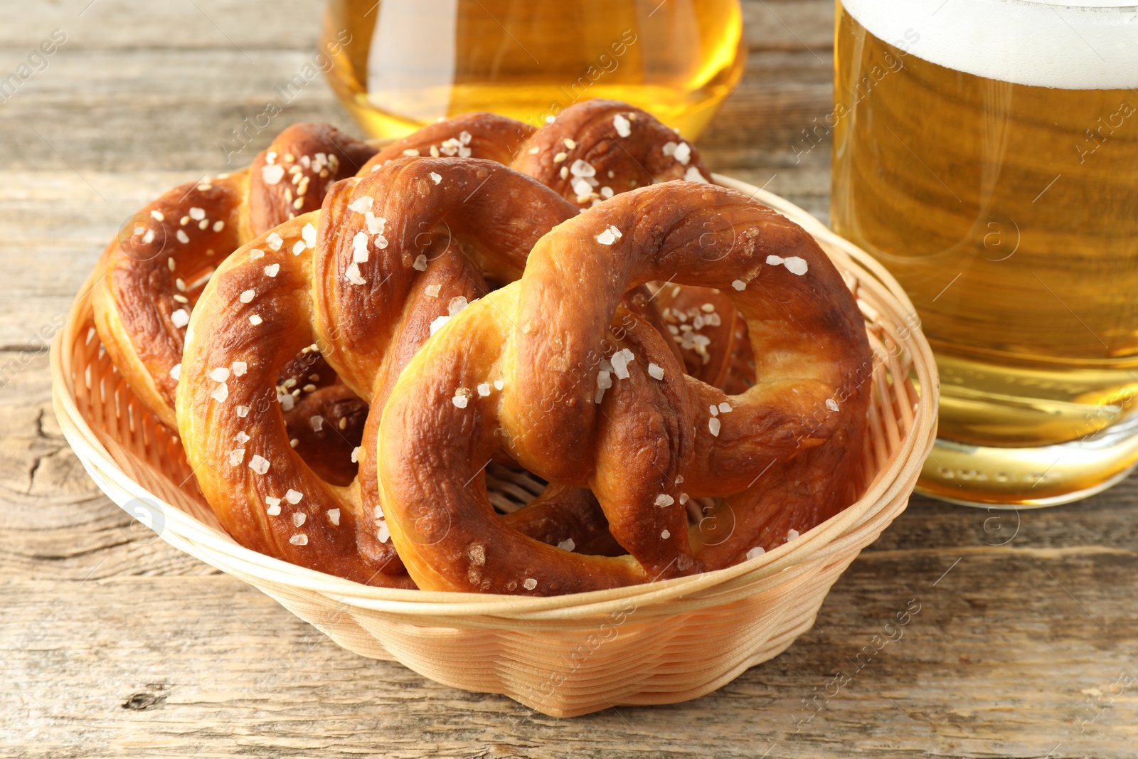 Tasty pretzels in basket and glasses of beer on wooden table, closeup Photo of Tasty pretzels in basket and glasses of beer on wooden table, closeup