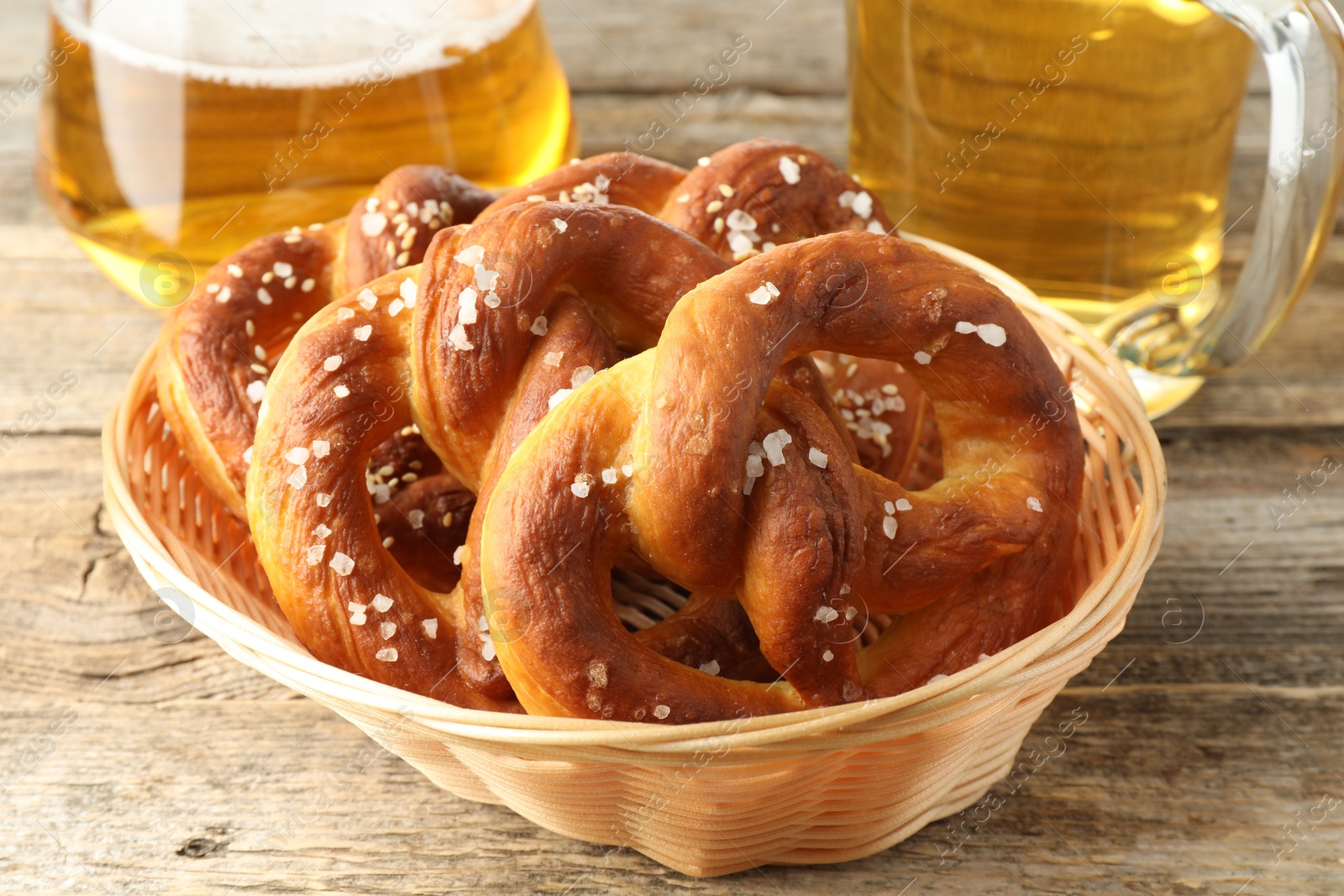 Tasty pretzels in basket and glasses of beer on wooden table, closeup Photo of Tasty pretzels in basket and glasses of beer on wooden table, closeup