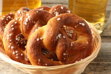 Photo of Tasty pretzels in basket on wooden table, closeup