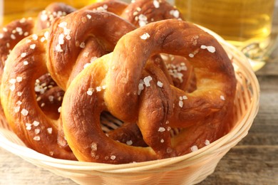 Photo of Tasty pretzels in basket on wooden table, closeup