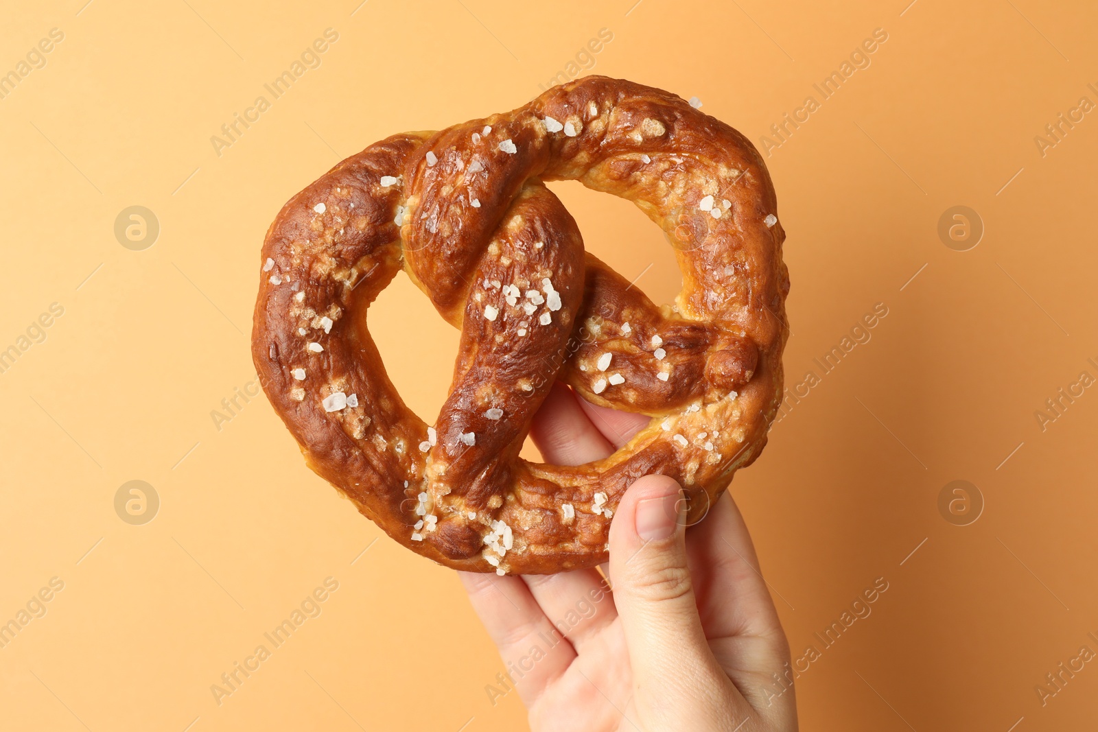 Woman with tasty pretzel on beige background, closeup Photo of Woman with tasty pretzel on beige background, closeup