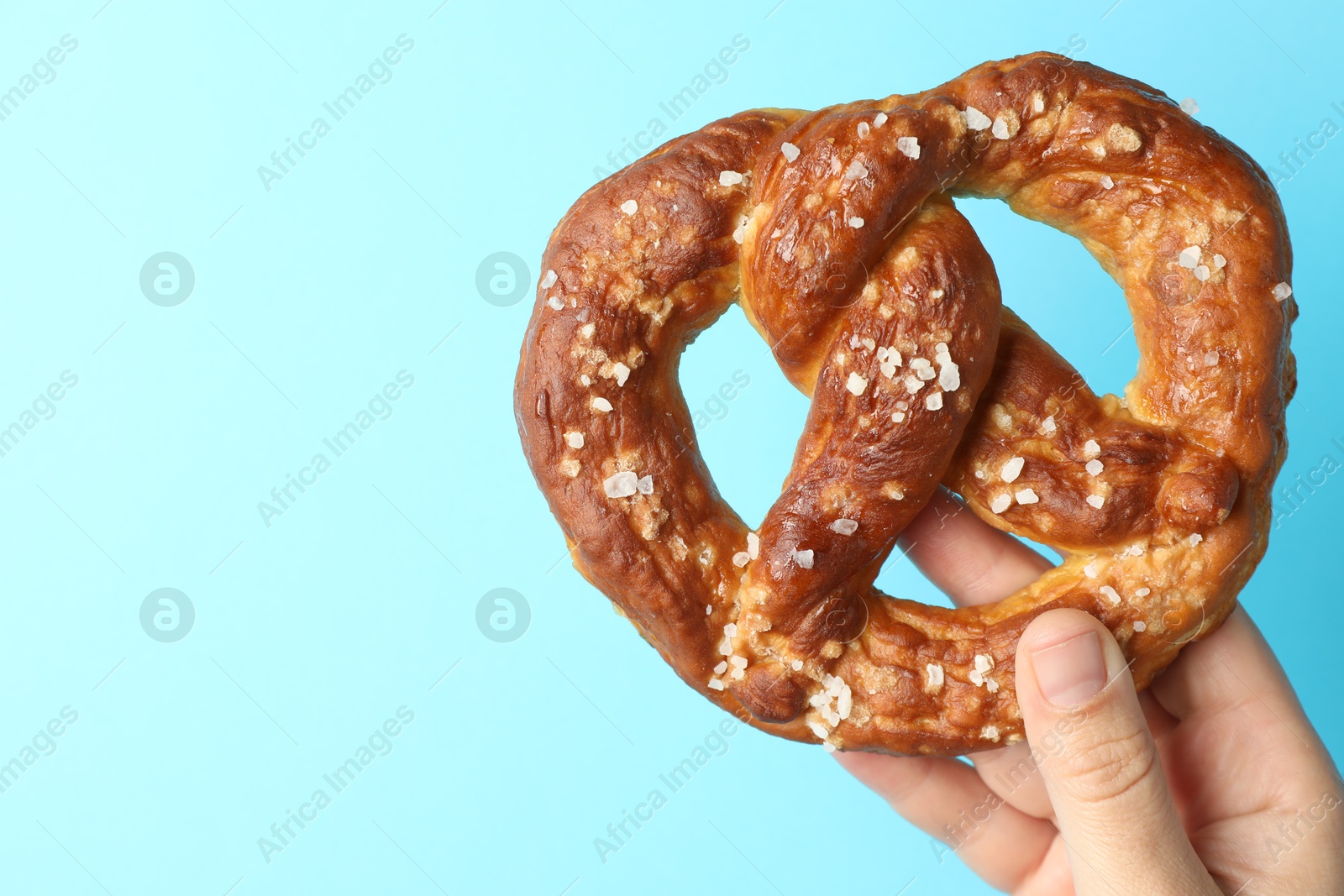 Woman with tasty pretzel on light blue background, closeup. Space for text Photo of Woman with tasty pretzel on light blue background, closeup. Space for text
