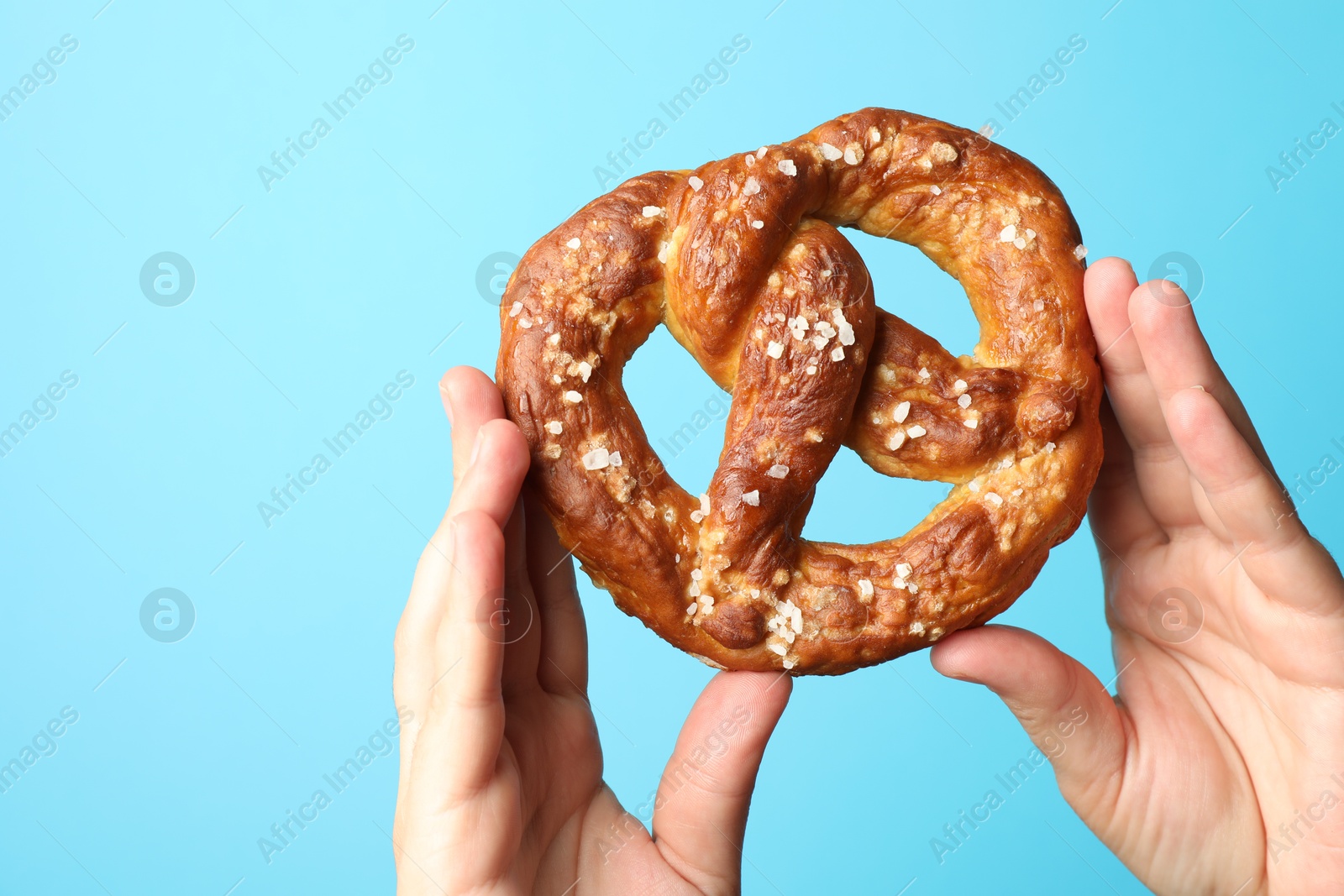 Woman with tasty pretzel on light blue background, closeup Photo of Woman with tasty pretzel on light blue background, closeup