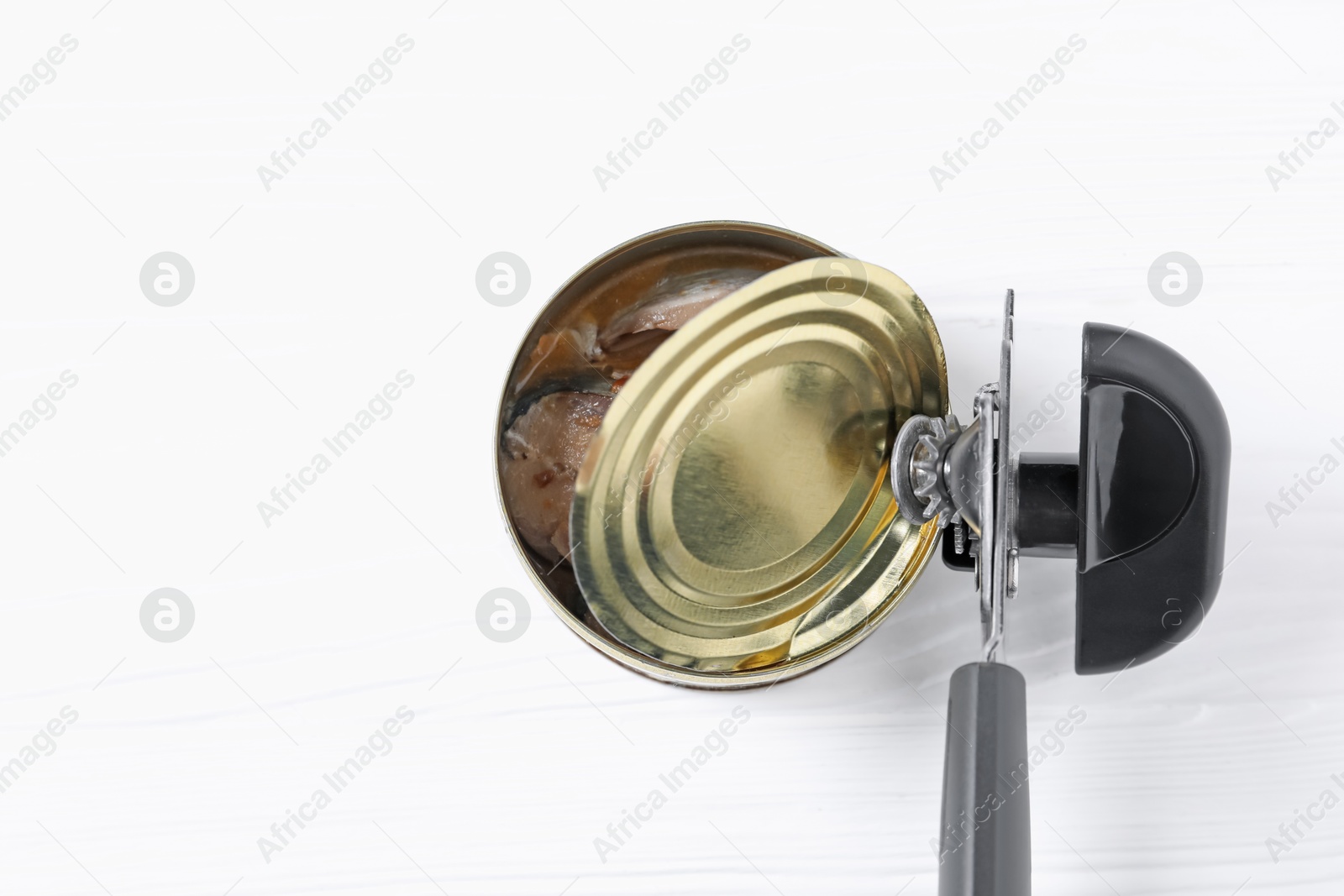 Can opener and tin with fish on white wooden table, top view. Space for text Photo of Can opener and tin with fish on white wooden table, top view. Space for text