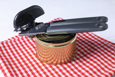 Photo of Can opener and tin on table, closeup