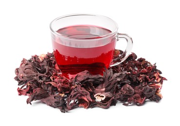 Photo of Delicious hibiscus tea in glass cup and dry roselle sepals isolated on white