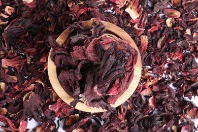 Photo of Hibiscus tea. Wooden bowl with dried roselle sepals on table, top view