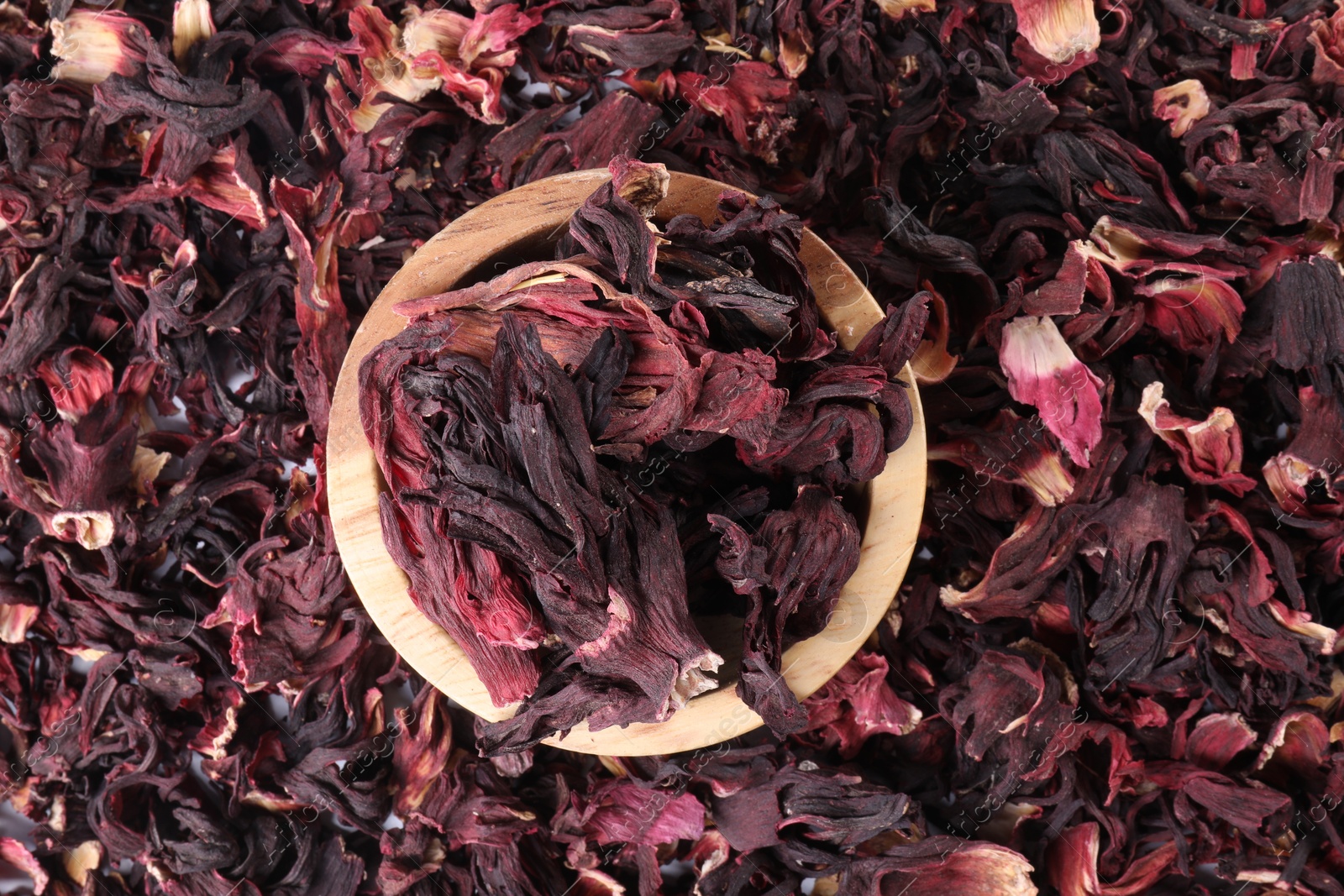 Hibiscus tea. Wooden bowl with dried roselle sepals on table, top view Photo of Hibiscus tea. Wooden bowl with dried roselle sepals on table, top view