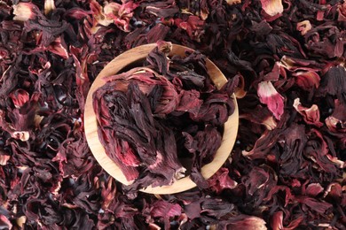 Photo of Hibiscus tea. Wooden bowl with dried roselle sepals on table, top view