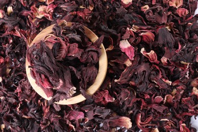 Photo of Hibiscus tea. Wooden bowl with dried roselle sepals on table, top view