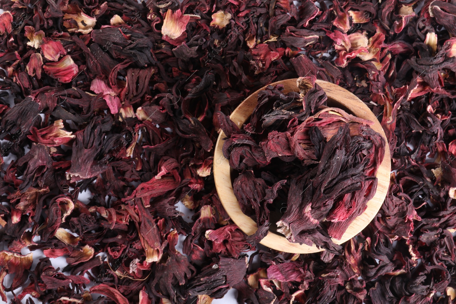 Hibiscus tea. Wooden bowl with dried roselle sepals on table, top view Photo of Hibiscus tea. Wooden bowl with dried roselle sepals on table, top view