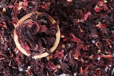 Photo of Hibiscus tea. Wooden bowl with dried roselle sepals on table, top view