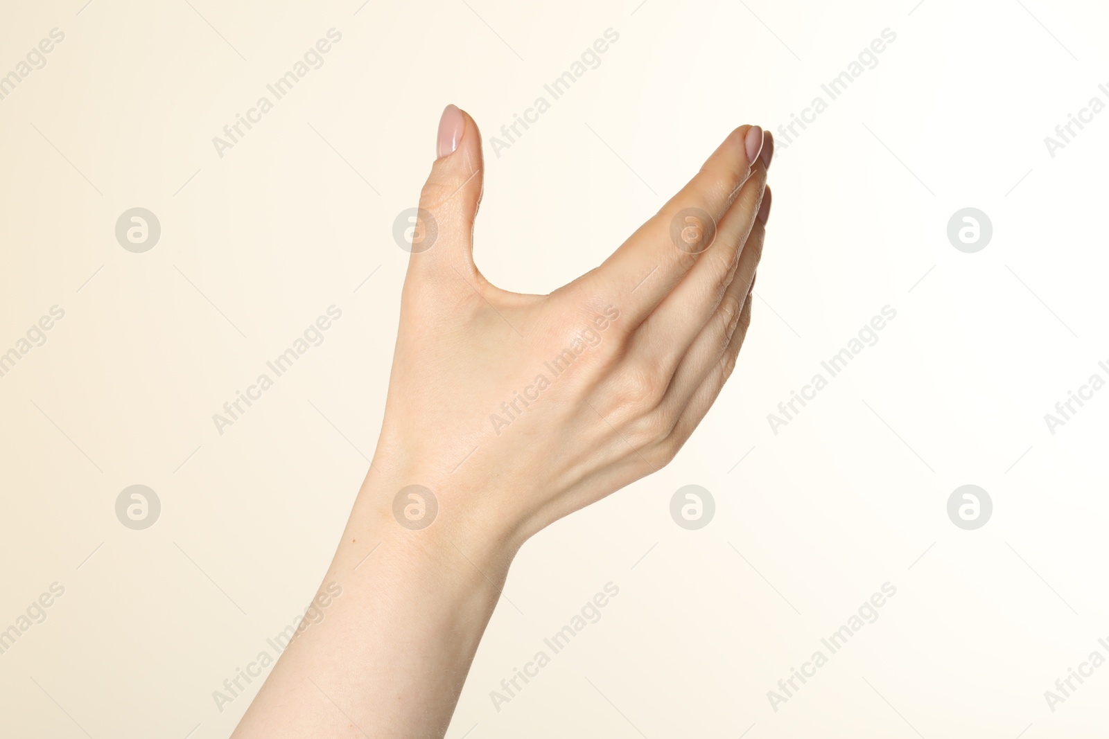 Woman holding something in hand on beige background, closeup Photo of Woman holding something in hand on beige background, closeup