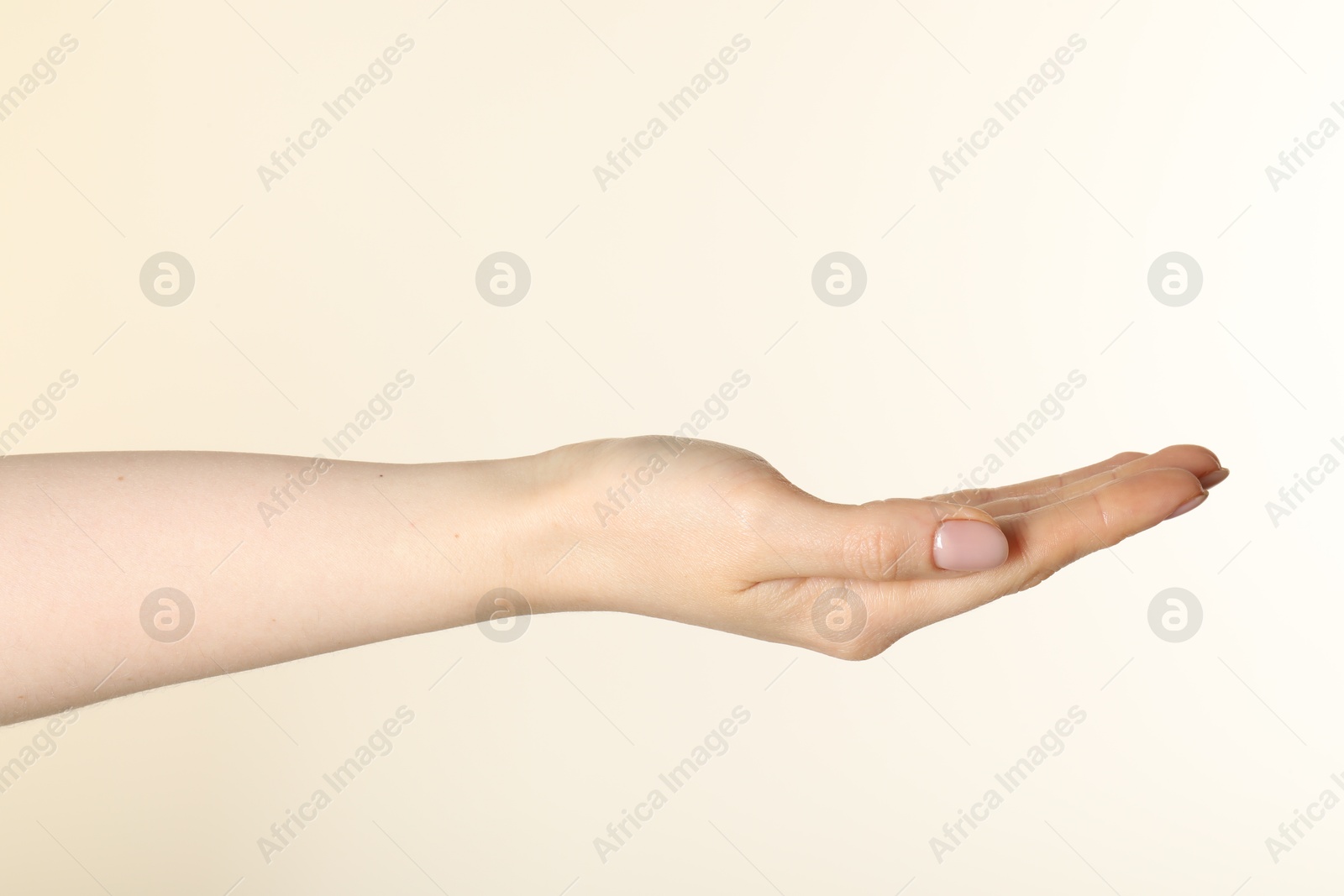 Woman holding something in hand on beige background, closeup Photo of Woman holding something in hand on beige background, closeup