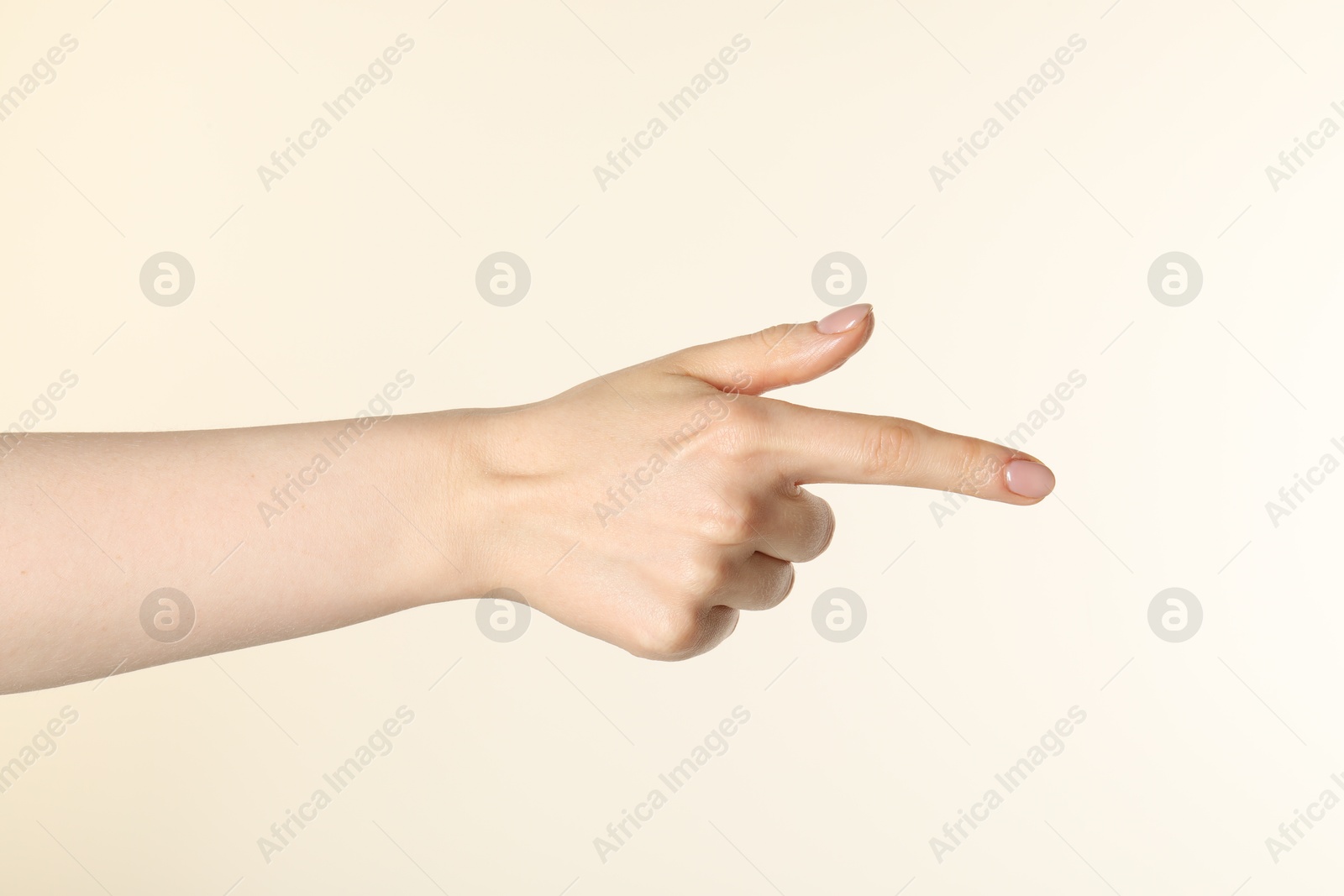 Woman holding something in hand on beige background, closeup Photo of Woman holding something in hand on beige background, closeup