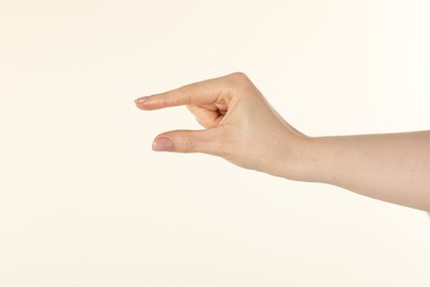 Photo of Woman holding something in hand on beige background, closeup