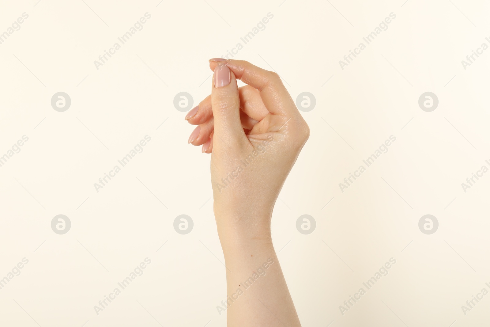 Woman holding something in hand on beige background, closeup Photo of Woman holding something in hand on beige background, closeup